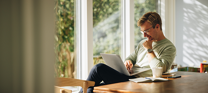 Man smiling and sitting with a laptop on his lap