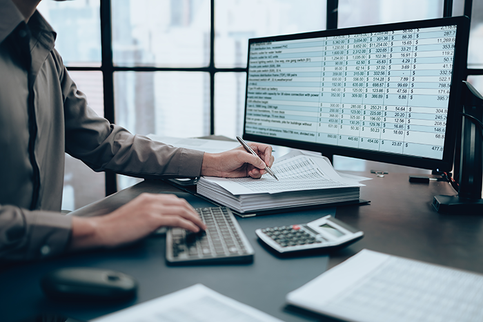 Man working a computer looking at business-related spreadsheets and documents